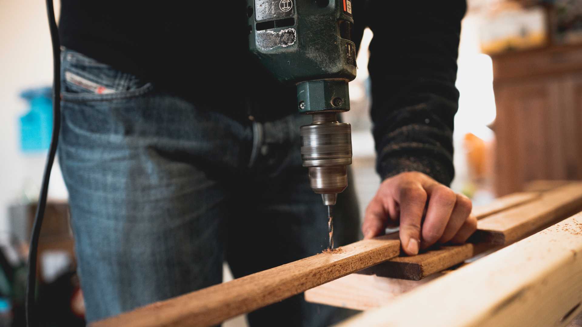 homme qui perce une planche de bois